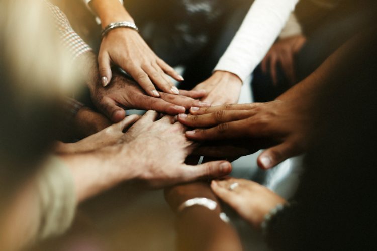 Closeup of diverse people joining their hands - idea of ending racism and encouraging diversity, equality and inclusion