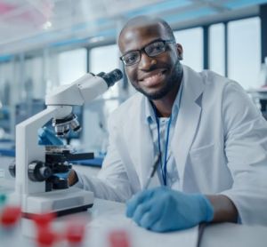 Black male scientist smiling at the camera at the bench of a research laboratory