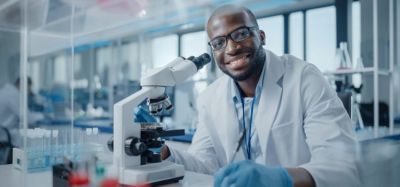 Black male scientist smiling at the camera at the bench of a research laboratory