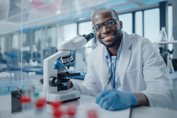 Black male scientist smiling at the camera at the bench of a research laboratory