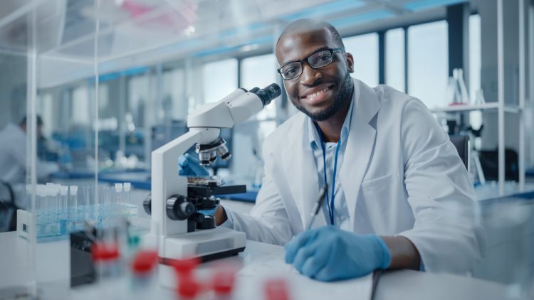 Black male scientist smiling at the camera at the bench of a research laboratory