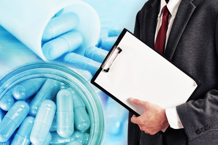 man holding a clipboard in a suit overlaid on a close up of blue pills in a tube - idea of drug evaluation/approvals