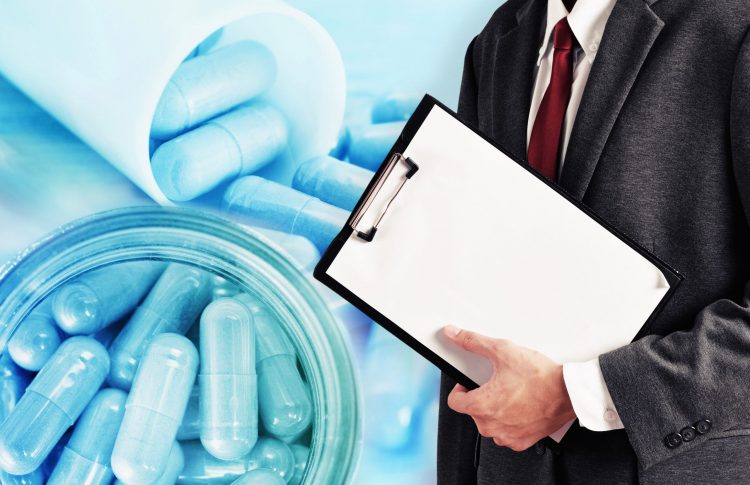 man holding a clipboard in a suit overlaid on a close up of blue pills in a tube - idea of drug evaluation/approvals