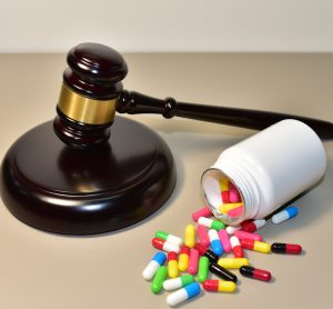 Judge's gavel next to a bottle on its side with colourful pills spilling out - idea of drug patents/regulations
