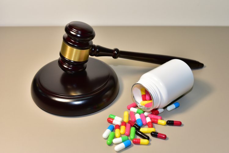 Judge's gavel next to a bottle on its side with colourful pills spilling out - idea of drug patents/regulations