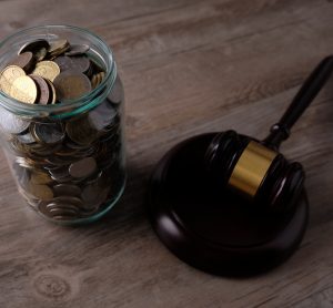 jar of US currency coins next to a wooden gavel and block