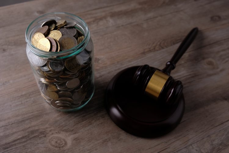 jar of US currency coins next to a wooden gavel and block