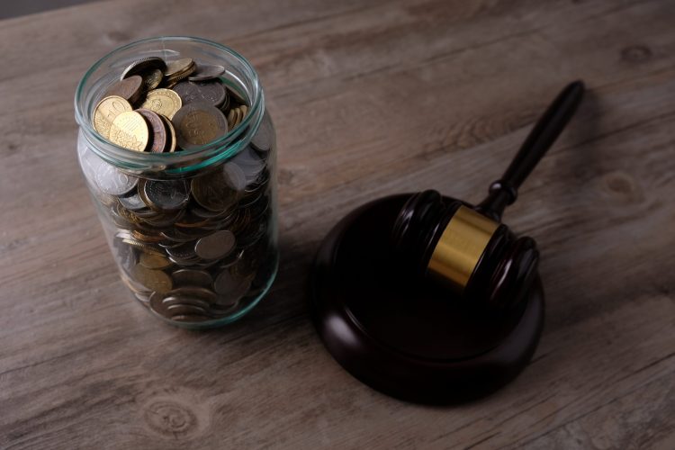 jar of US currency coins next to a wooden gavel and block