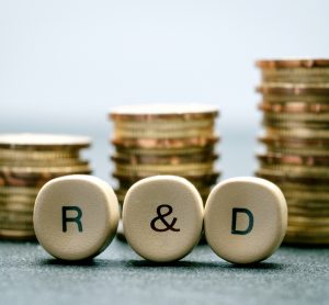 Idea of research funding - R&D spelt out on counters in front of stacks of coins