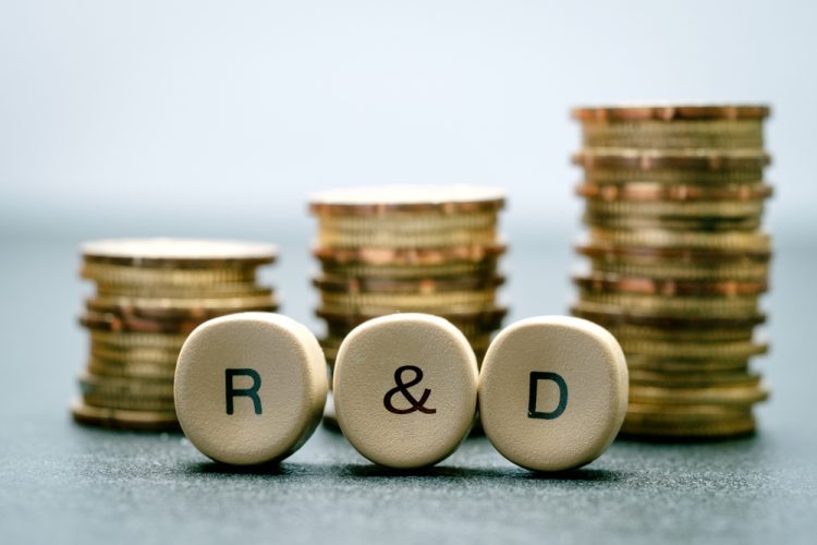 Idea of research funding - R&D spelt out on counters in front of stacks of coins