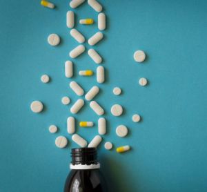 white pills spilling from a bottle forming the shape of a DNA double helix - idea of treatment for inherited/genetic disease