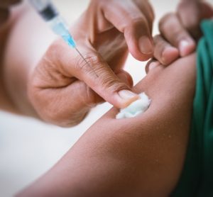 Doctor injecting a patient in the upper arm using a syringe