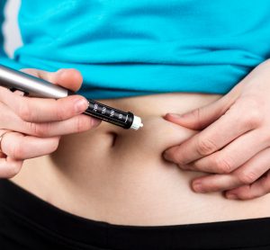 woman using prefilled insulin syringe to inject into the abdomen
