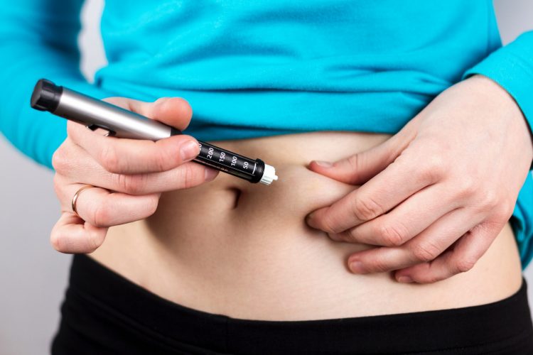 woman using prefilled insulin syringe to inject into the abdomen