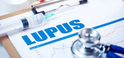 concept of lupus treatment or drug development - word lupus typed on page surrounded by colourful pills, a syringe and stethoscope