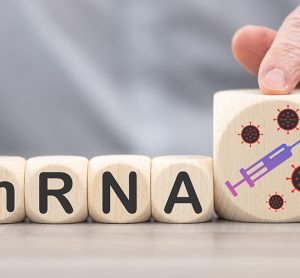 person's hands moving wooden blocks labelled with the letters mRNA and a picture of a syringe - idea of mRNA-based vaccines