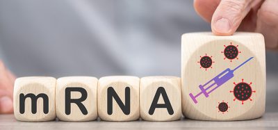 person's hands moving wooden blocks labelled with the letters mRNA and a picture of a syringe - idea of mRNA-based vaccines