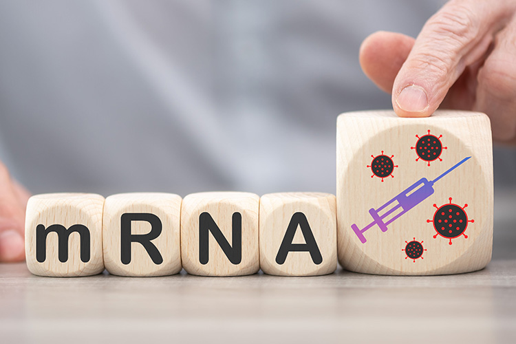 person's hands moving wooden blocks labelled with the letters mRNA and a picture of a syringe - idea of mRNA-based vaccines