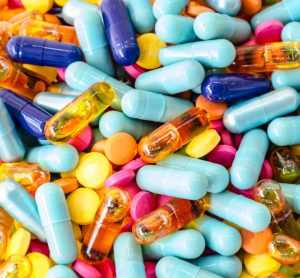 various colourful capsules in a pile filling the whole image - idea of supply of medicines