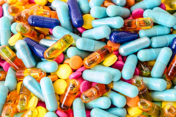 various colourful capsules in a pile filling the whole image - idea of supply of medicines