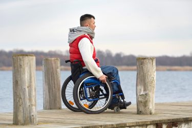 man in a wheelchair looking over a lake
