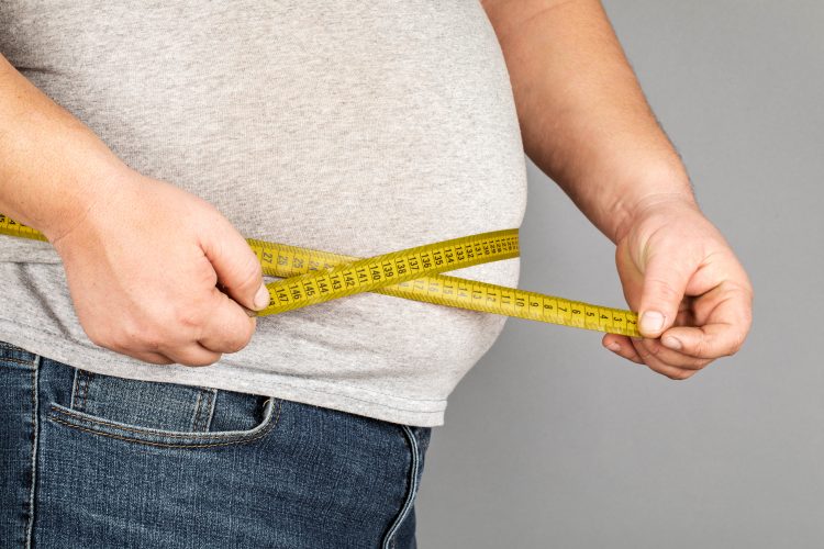 fat man measuring his stomach with a tape measure