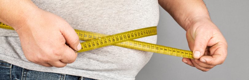 Man with tape measure depicting obesity