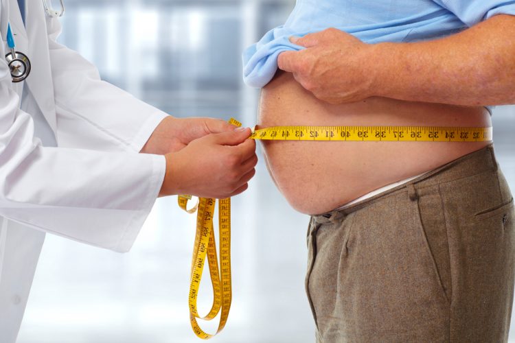 Doctor measuring the stomach of an overweight man