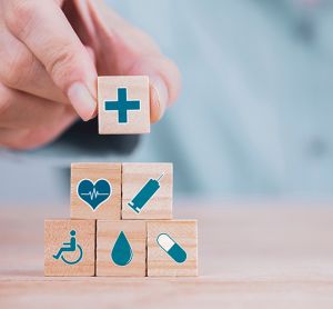 close up of a person stacking wooden blocks with various health and medicine related symbols