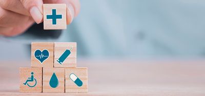 close up of a person stacking wooden blocks with various health and medicine related symbols