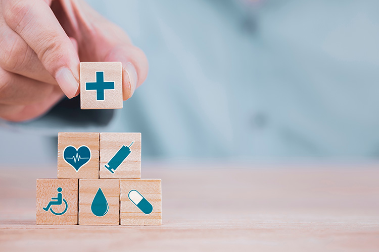 close up of a person stacking wooden blocks with various health and medicine related symbols