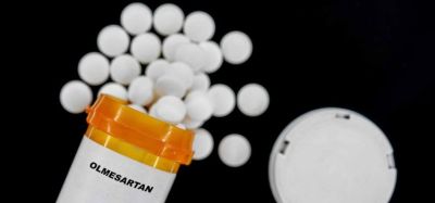 Olmesartan white pills spilling from an orange prescription medicines bottle
