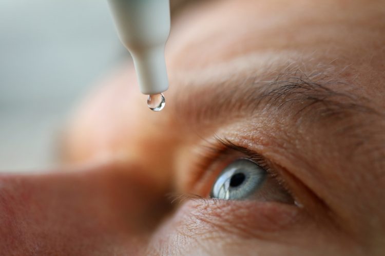 close up of man using eye drops