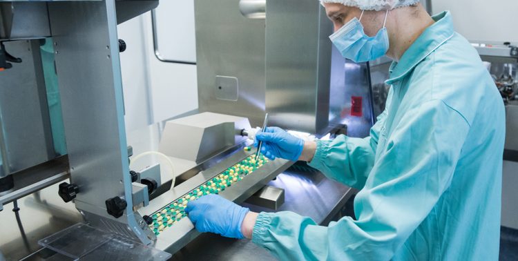 Technician checking solid oral pills in manufacturing facility