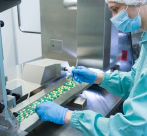 Technician checking solid oral pills in manufacturing facility