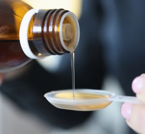 close up of an oral solution being poured onto a medicine spoon