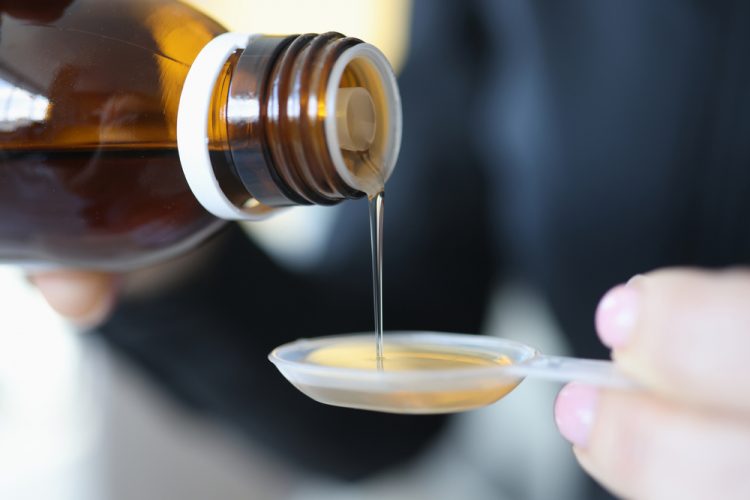 close up of an oral solution being poured onto a medicine spoon