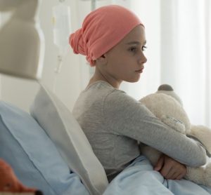 Sick child in a hospital bed holding a teddy