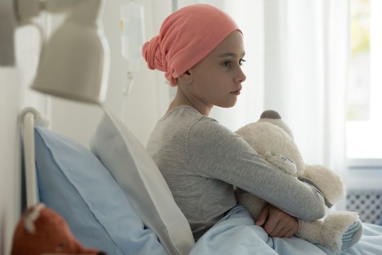 Sick child in a hospital bed holding a teddy