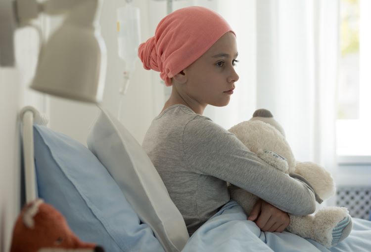 Sick child in a hospital bed holding a teddy