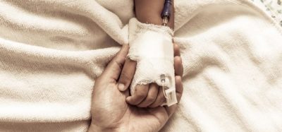 Close up of an adult holding the hand of a child recieving cancer treatment through IV - idea of paediatric oncology treatment