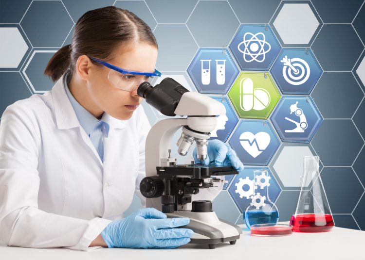 woman looking down a microscope with a graphic indicative of medical/pharmaceutical research behind