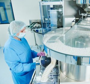 Pharmaceutical manufacturing facility worker operating a blister packaging machine