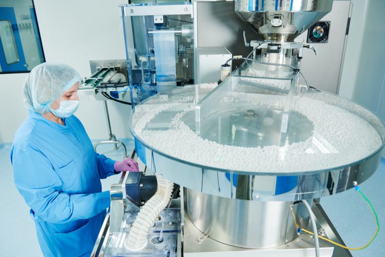 Pharmaceutical manufacturing facility worker operating a blister packaging machine