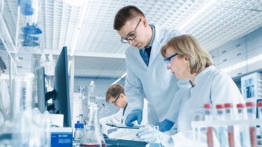 In Modern Laboratory Senior Female Scientist Has Discussion with Younger Male Laboratory Assistant