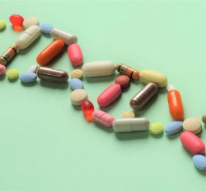 idea of pharmacogenomics and personalised prescribing - collection of prescription capsules and tablets in the shape of DNA running diagonally across a light green background