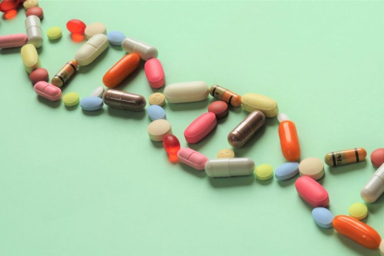 pharmacogenomics and personal prescription idea - set of DNA shaped prescription capsules and tablets running diagonally across a light green background