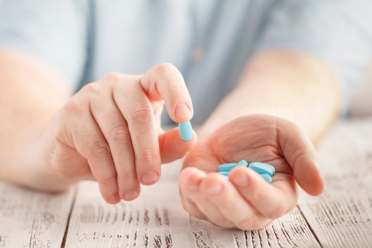 Patient holding blue pills in their hands