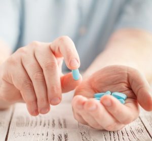 Patient holding blue pills in their hands