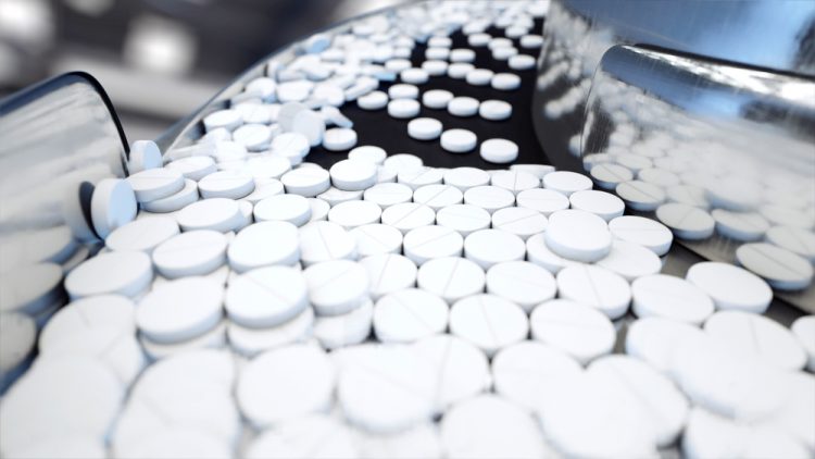 white tablets on a pharmaceutical production line - idea of tablet manufacturing